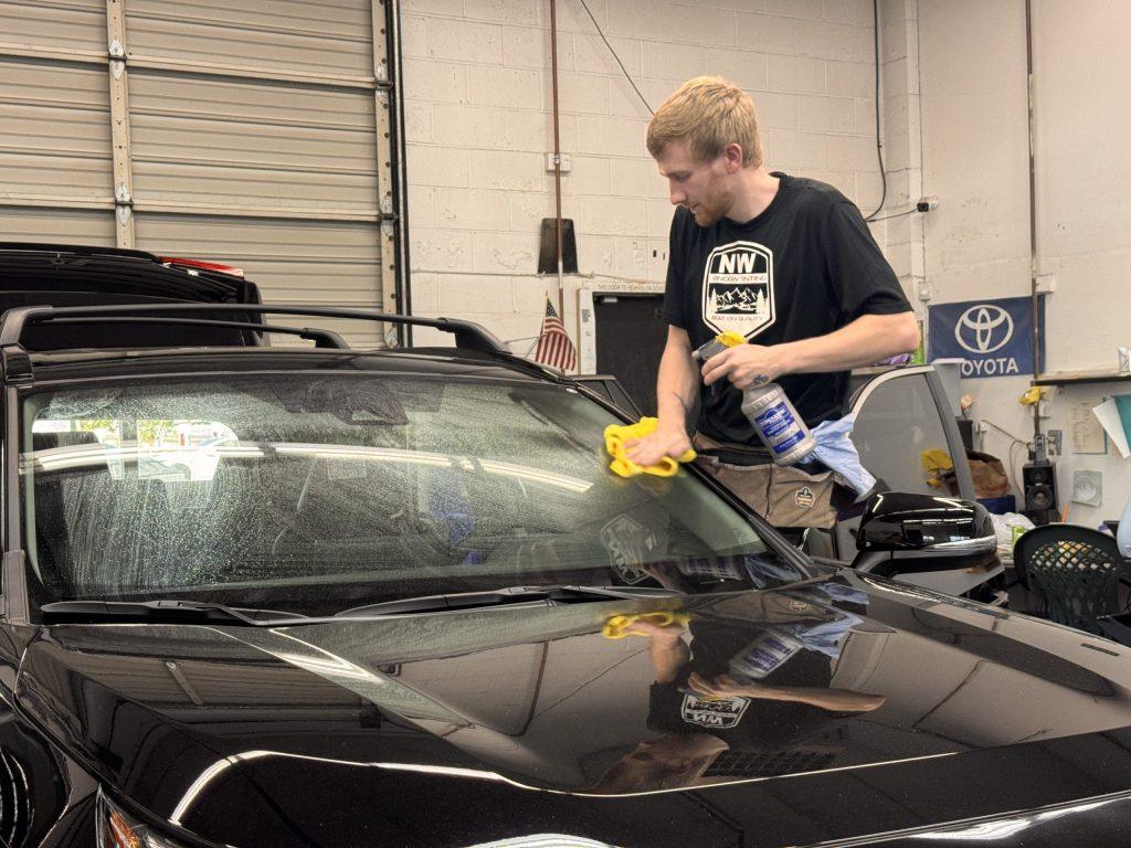 Technician cleaning windshield before window tint installation at NW Window Tinting